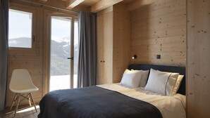 A bedroom with a bed, a chair, and a view of the mountains through a large window. - Chalet in Les Masses with garden (Les Masses)