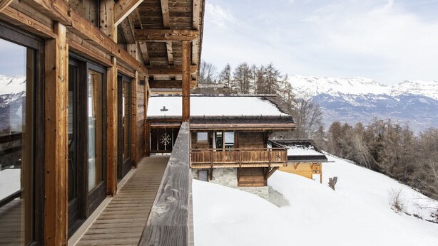 A wooden cabin with large windows and a balcony overlooking a snowy mountain landscape. - Chalet in Les Masses with garden (Les Masses)