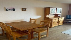 A dining area with a wooden table and chairs, a cabinet with a decorative top, and a painting on the wall.