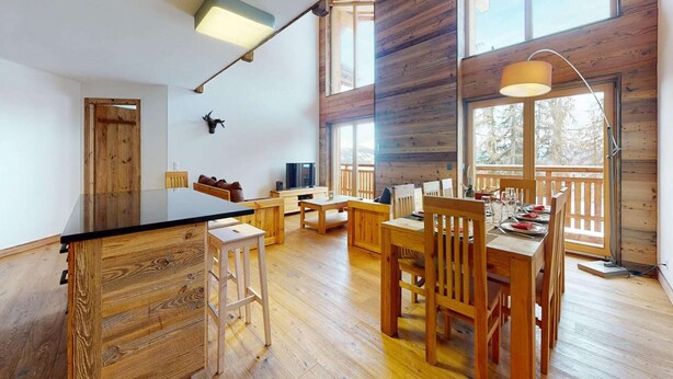 Amplia sala de estar con una gran mesa de comedor de madera, asientos cómodos y una televisión.
