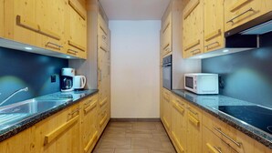 Une cuisine étroite avec des meubles en bois, un évier en acier inoxydable, une machine à café et un four à micro-ondes.