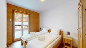 Une chambre avec deux lits simples, des murs en bois, une armoire en bois et une table de chevet avec une lampe.