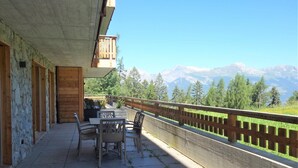 Un balcon avec une table et des chaises, donnant sur un paysage montagneux.