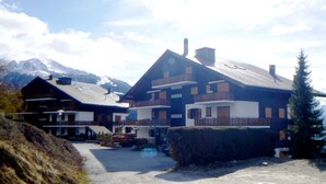 A two-story chalet with a balcony, a ski lift in the background, and a mountain in the distance. - Apartment with Rhone valley view (Veysonnaz)
