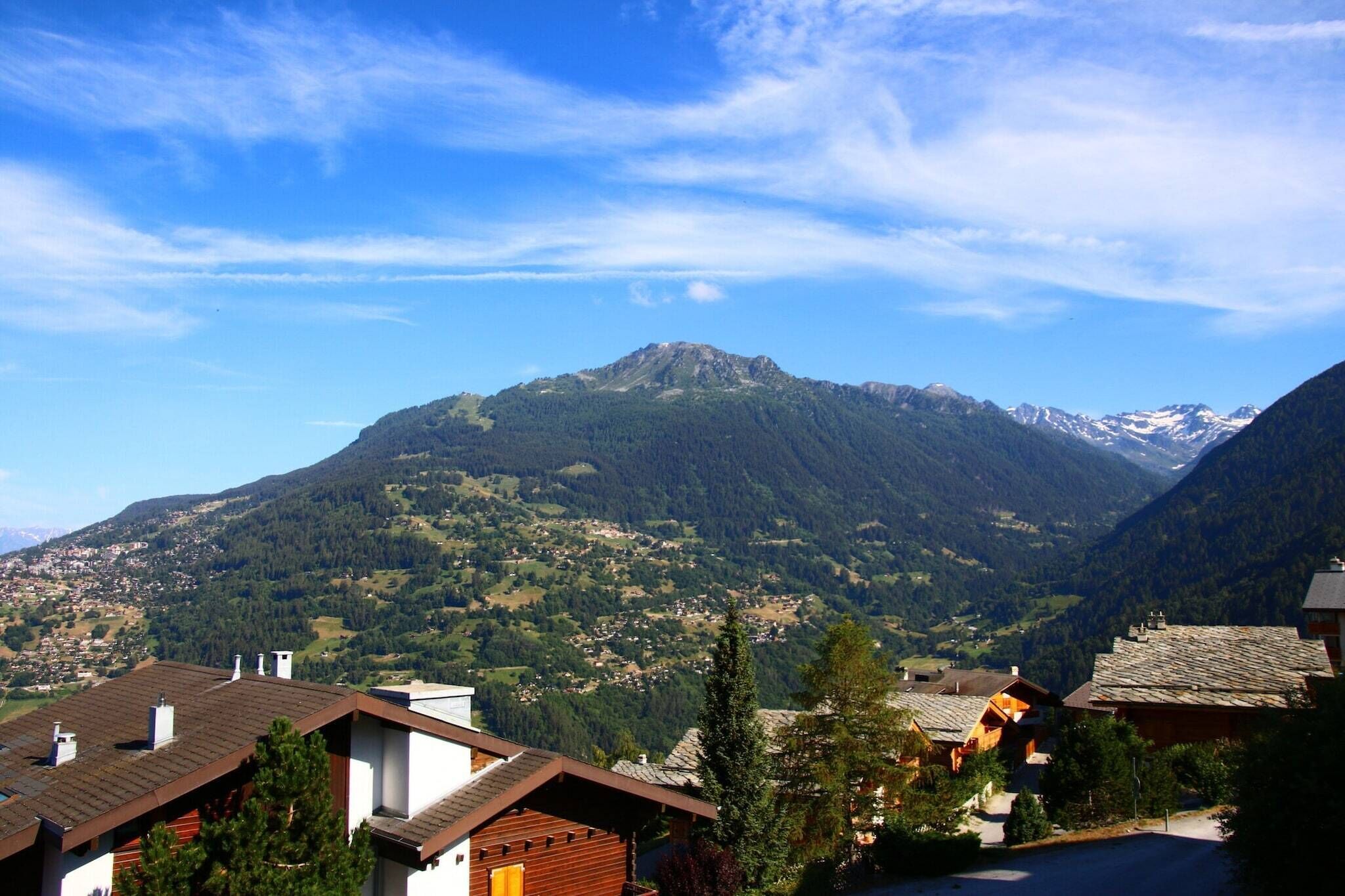 A mountain village with traditional wooden houses and a prominent mountain in the background.