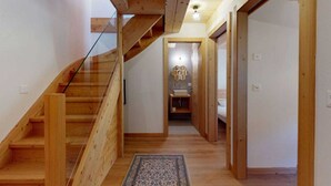 A wooden staircase leading to a bathroom with a sink and a hexagonal light fixture.
