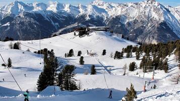 A ski resort with a chairlift, snow-covered slopes, and a mountain backdrop.