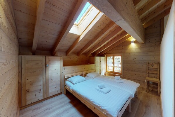 A wooden cabin bedroom with a bunk bed, a skylight, and a small window.