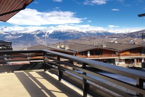 Un hotel con varias construcciones, un balcón de madera y una montaña nevada al fondo.