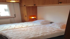 Un dormitorio con cama, cabecera de madera y una lámpara de pared.