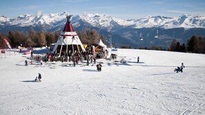 Ein mit Schnee bedeckter Ski-Hang mit einem Totempfahl und einer Seilbahn im Hintergrund.