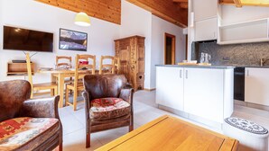 Un salon chaleureux avec des meubles en bois, un coin repas et une cuisine dotée de meubles blancs et de plans de travail en granit.