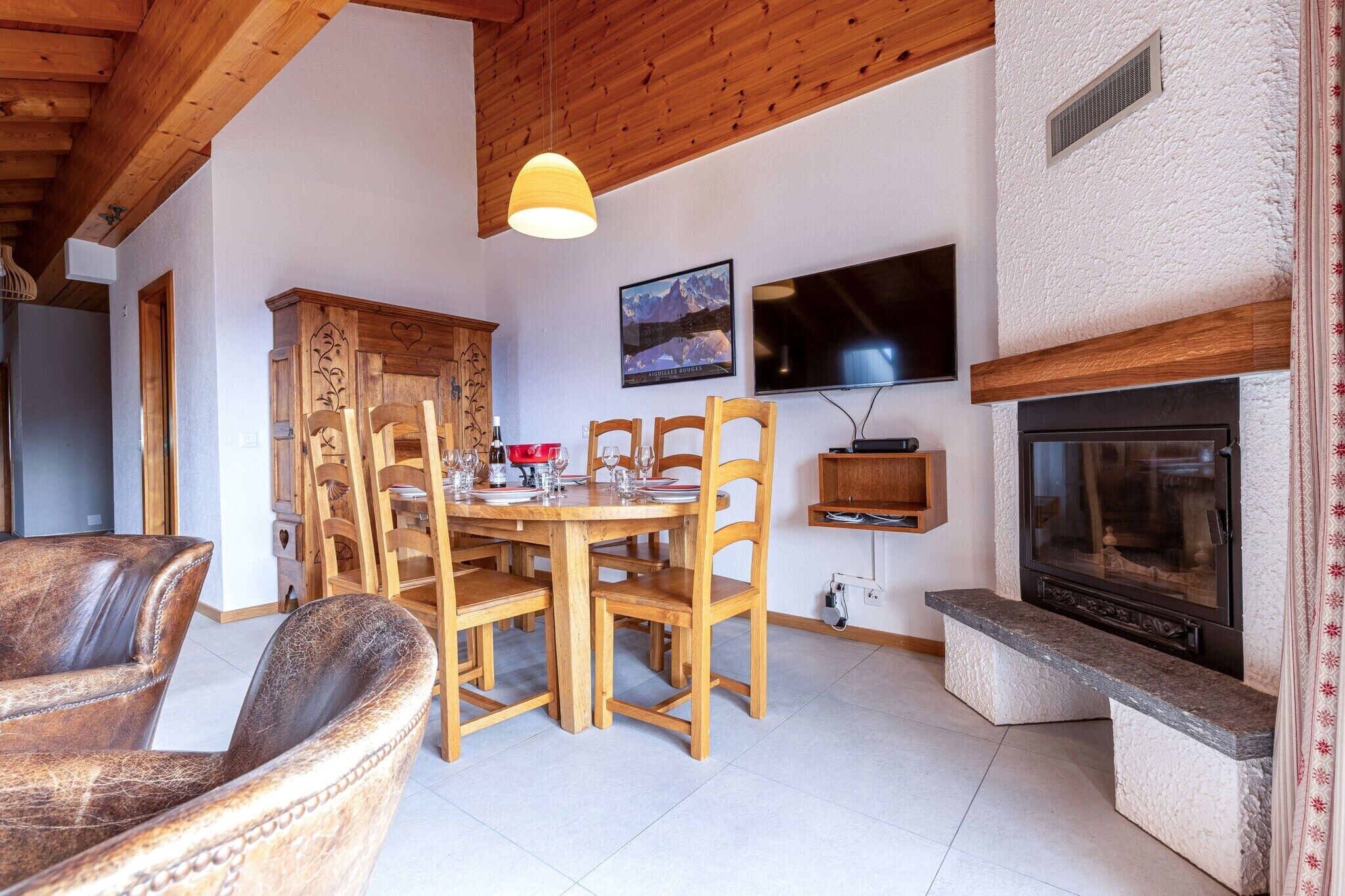 Una zona pranzo accogliente con arredi in legno, un camino e una TV a parete.