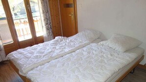 A single-bed room with a wooden frame, a white quilted mattress, and a wooden floor. - Apartment for 10 in Veysonnaz (Veysonnaz)