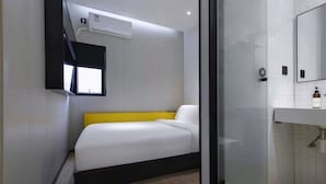 A compact hotel room with a bed, a small window, a mirror, and a bathroom with a sink and toiletries. - yibaijiudianlangaoluditiezhandian (Shanghai)