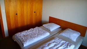 A single bed with a wooden headboard, a wooden wardrobe, and a plain wall. - Apartment, 250m from cable car (Veysonnaz)
