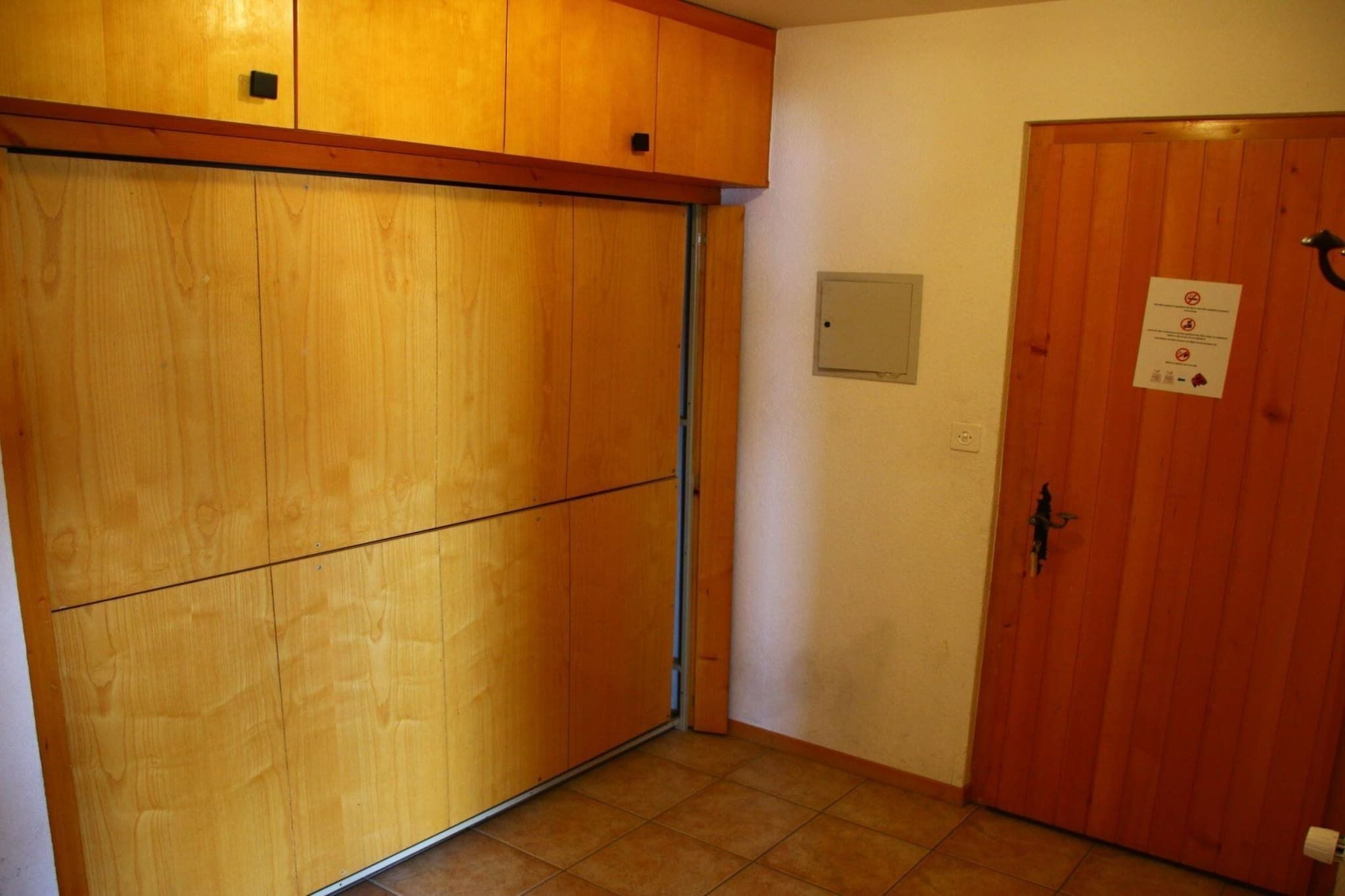 A room with a sliding wooden door, a closed wooden door with a sign, and a tiled floor.