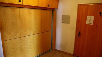 A room with a sliding wooden door, a closed wooden door with a sign, and a tiled floor.