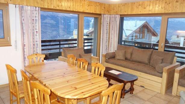 A wooden-paneled room with a dining table and chairs, a sofa, and large windows offering mountain views. - Apartment, 250m from cable car (Veysonnaz)