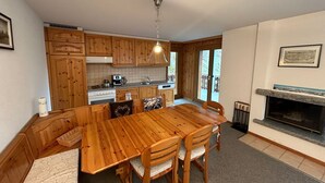 A kitchen with wooden cabinets, a dining table with chairs, a built-in oven, and a fireplace.
