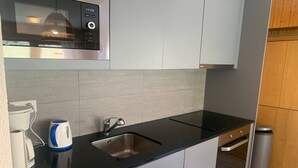 A modern kitchen with a black countertop, stainless steel sink, and a kettle. - Apartment in Veysonnaz near Ski area (Veysonnaz)