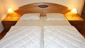 Un lit double avec une tête de lit en bois, deux tables de chevet avec des lampes et une petite fenêtre au-dessus de la tête de lit.
