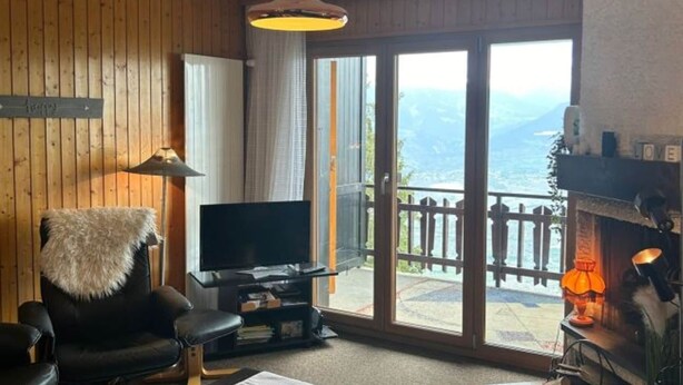 Un salon chaleureux avec une télévision, une cheminée et une vue sur les montagnes, grâce à de grandes portes coulissantes.