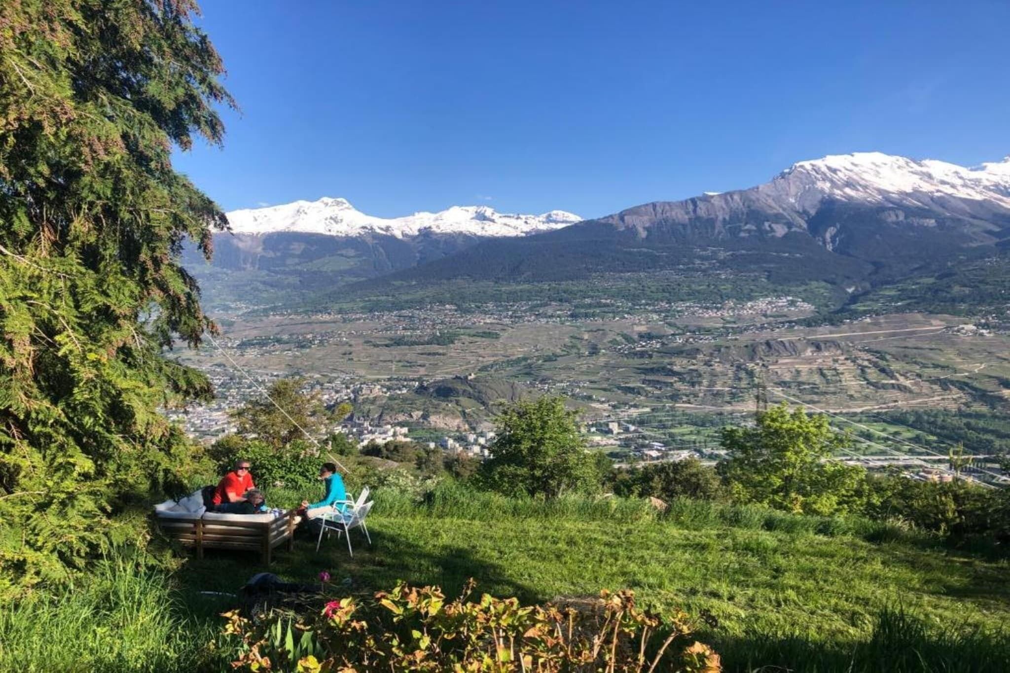 Een bergachtig landschap met een vallei en een kleine groep mensen die op een bank zitten.
