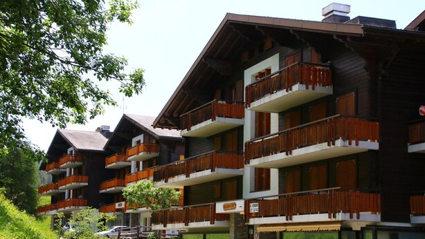 A multi-story hotel with balconies, a stone facade, and a sign indicating availability. - Marvelous apartment with balcony (Les Agettes)
