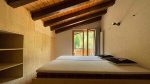 A bedroom with a wooden ceiling, a bed with a mattress and pillows, and a window with a view of greenery. - Marvelous apartment with balcony (Les Agettes)