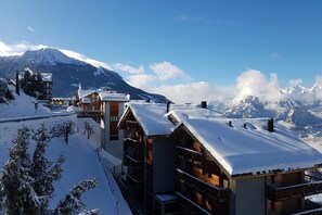 A snow-covered mountain resort with wooden buildings and a clear view of the mountains.