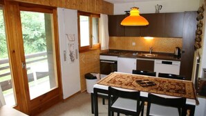 Une cuisine de taille réduite avec des meubles en bois, une table à manger avec des chaises et une grande fenêtre.