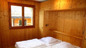 Une pièce en bois avec un lit, une fenêtre et une porte.