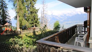 Un balcon avec vue sur un terrain de jeux et les montagnes.