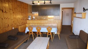 Une pièce chaleureuse avec des murs en bois, une table à manger avec des chaises et deux canapés.