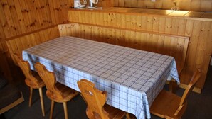 Un intérieur en bois avec une table dressée pour quatre personnes, équipée d’une machine à café et d’une bouilloire.
