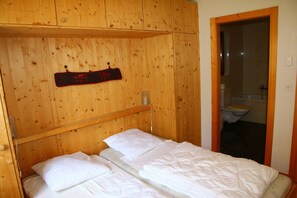 A wooden cabin-style room with a bed, a wooden headboard, and a wooden wall with a mounted plaque.