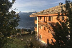 Una cabaña de madera con balcón con vistas a un paisaje montañoso.