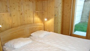 Un dormitori amb panells de fusta, un llit, almoinos i una tauleta de nit.