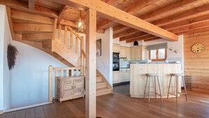 A wooden interior with a staircase, kitchen, and bar area. - Chalet in Veysonnaz with hot tub (Veysonnaz)