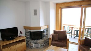 Un salon avec une cheminée en pierre, un téléviseur et une table basse en bois.