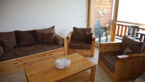 Un salon aménagé avec des meubles en bois, comprenant un canapé, deux fauteuils et une table basse.