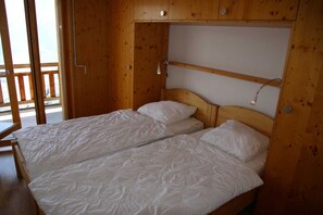Ein Zimmer aus Holz mit einem Bett, einem kleinen Tisch und einem Fenster mit Blick.
