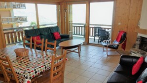 A cozy room with a dining table, chairs, a sofa, and a fireplace. - Spacious apartment with fireplace (Veysonnaz)