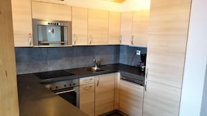 Une cuisine moderne équipée d’un four encastré, d’une plaque de cuisson et d’un lave-vaisselle.