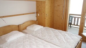 Ein Schlafzimmer aus Holz mit zwei Betten, einem Holzkopfstück und einem Balkon mit einem Stuhl.