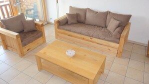 Eine Holz-Sofa- und Sesselgruppe mit passendem Couchtisch in einem Raum mit Fliesenboden.