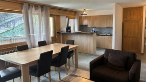 Eine moderne Küche mit Holzausbau, eine Essecke mit Tisch und Stühlen und eine gemütliche Sitzecke mit einer Couch.