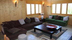 A wooden interior with a brown sofa, a green sofa, and a coffee table. - Chalet in Veysonnaz with mountain view (Veysonnaz)