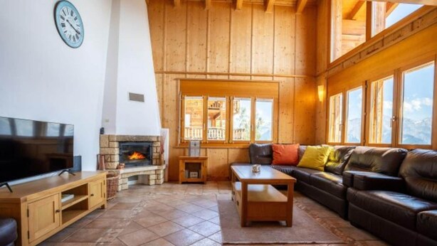 A cozy living room with a fireplace, wooden furniture, and large windows offering a mountain view. - Chalet in Veysonnaz with mountain view (Veysonnaz)